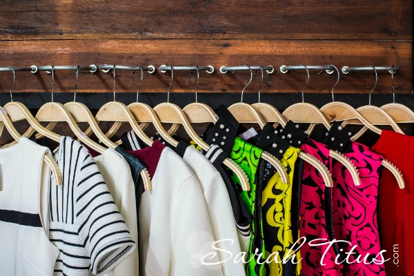 Many blouses on hangers in the dressing room.