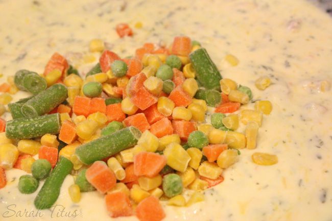 Adding frozen mixed vegetables to sauce mixture in large pan