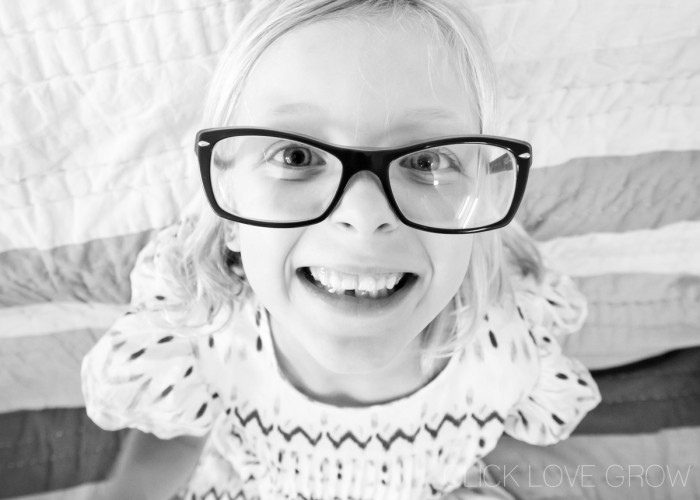 Black and white photo of a smiling girl with big glasses