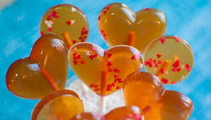 A bunch of yummy gold and red easy honey lollipop on a blue background!