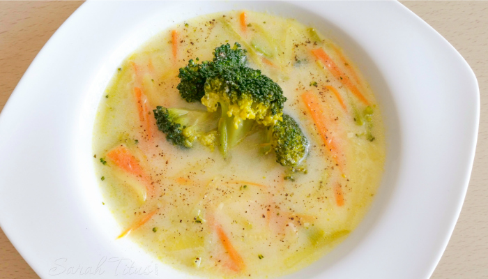 Appetizing Greek Avgolemono Vegetable Soup in a white bowl on a wood table