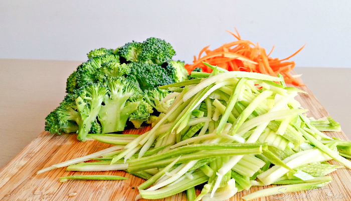 Julienne zucchini and carrots on a cutting board with broccoli for the Greek Avgolemono Vegetable Soup