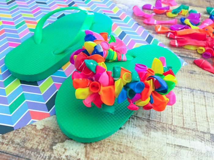 One green flip flop completely finished with colorful balloons tied on to the green straps