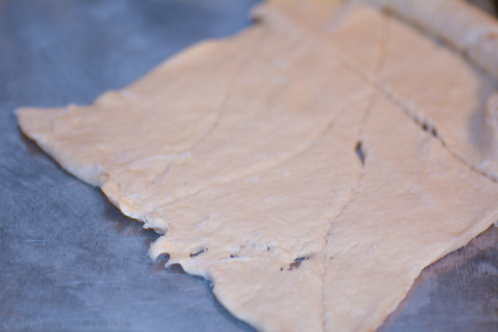 Crescent roll dough spread out on a parchment lined baking sheet for the Cherry Cheesecake Crescent Ring 