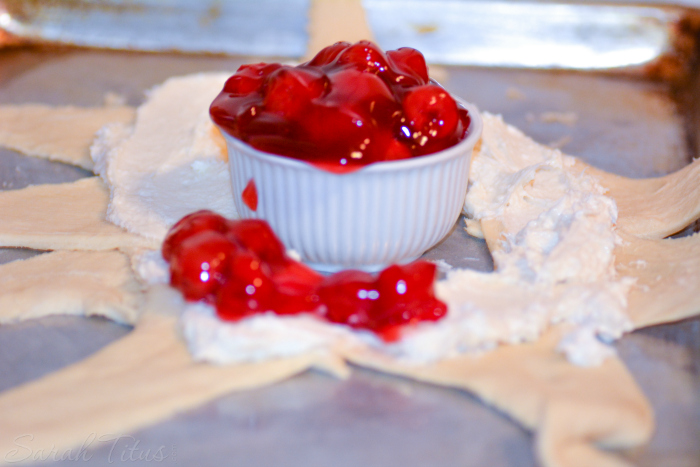 Crescent roll dough spread with cream cheese and a beautiful bowl full of red cherry pie filling