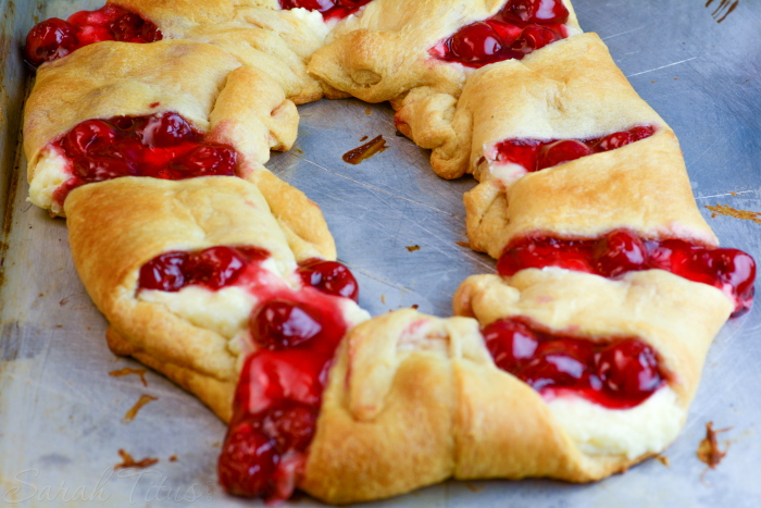 The freshly baked Cherry Cheesecake Crescent Ring on a parchment lined baking sheet