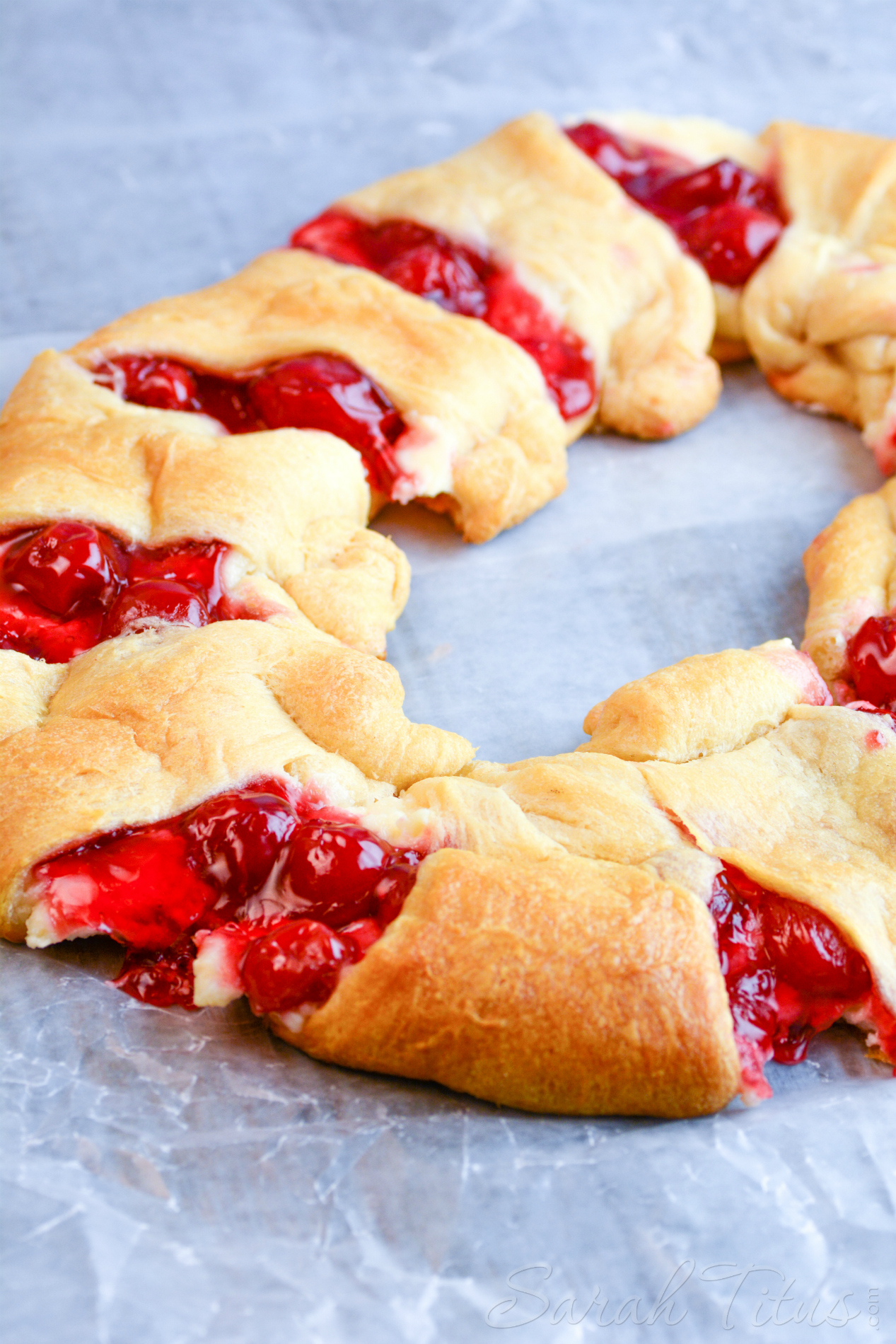 The freshly baked Cherry Cheesecake Crescent Ring on a parchment lined baking sheet