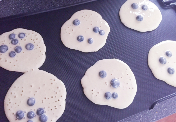 Blueberry pancakes cooking on a griddle