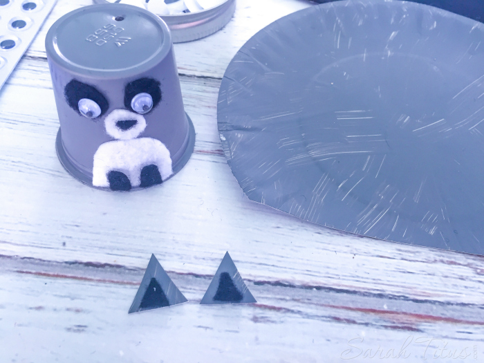 Add eyes and nose onto K cup to make raccoon face and make little raccoon ears