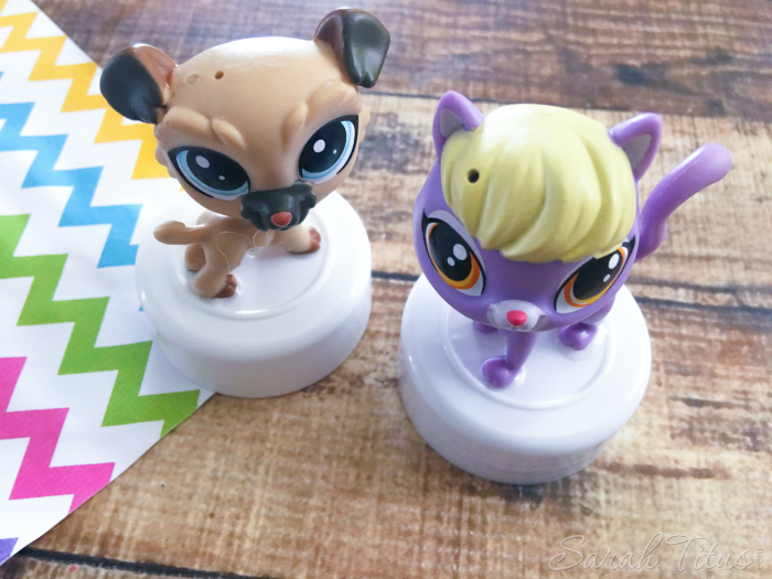 Littlest Pet Shop characters glued to small lids sitting on a wood table