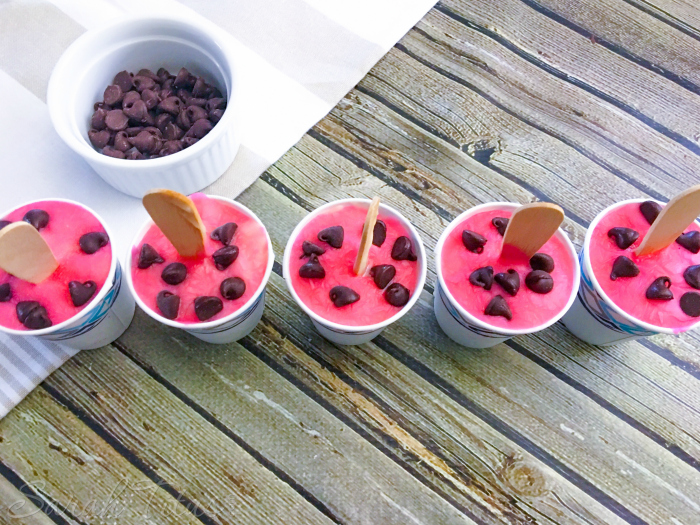Ready to freeze Watermelon Pudding Pops with pink pudding on the top and sprinkled with chocolate chips in cups on a table