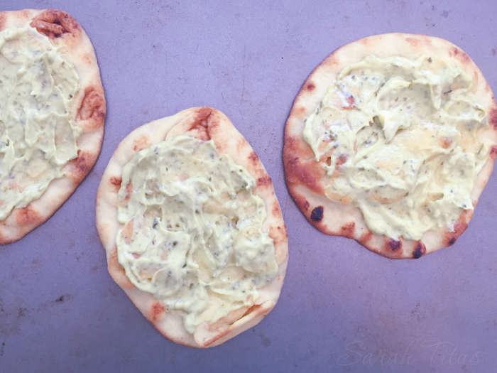 Spreading the pesto mayo mixture over each naan bread.