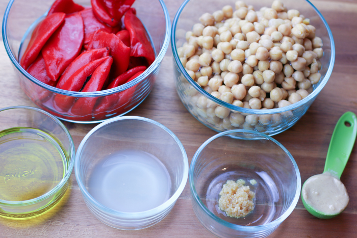 Pyrex glass dishes with ingredients for roasted red pepper hummus: chickpeas, lemon juice, garlic, roasted red peppers, olive oil, Himalayan Sea Salt, tahini and water