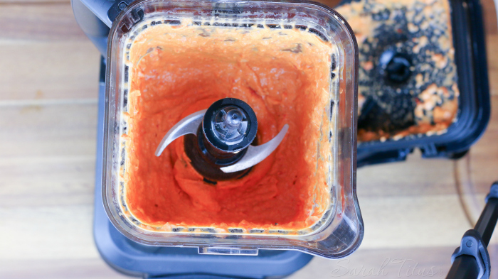 Fully blended roasted red pepper hummus in a blender on a counter