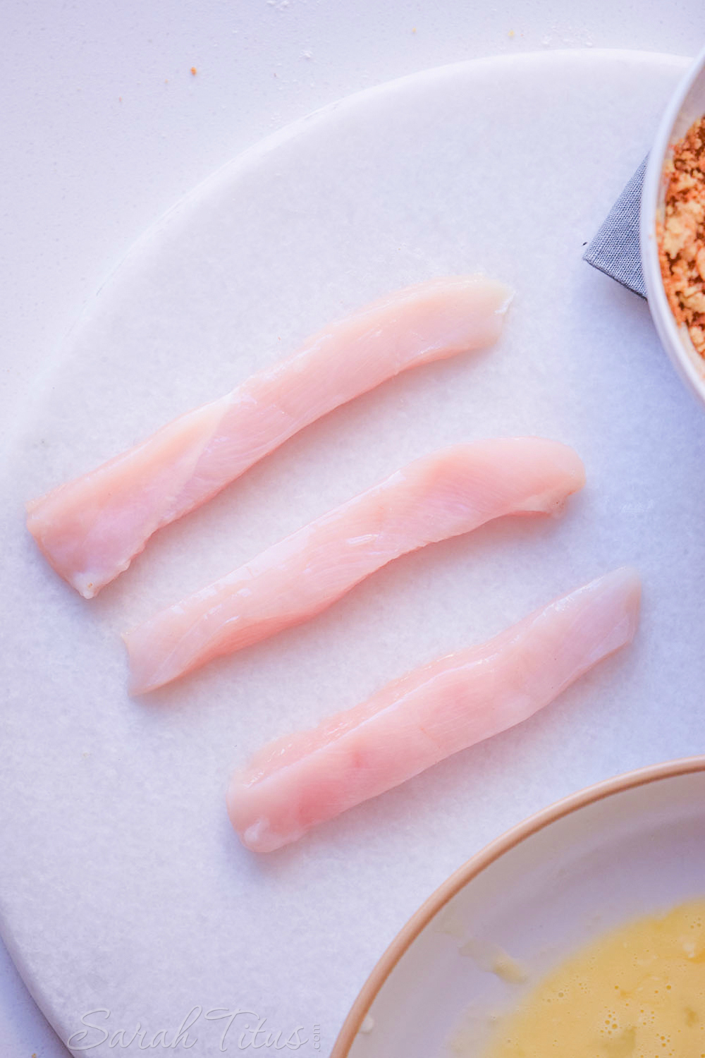 Large chicken breast cut into rectangle strips on a white plate