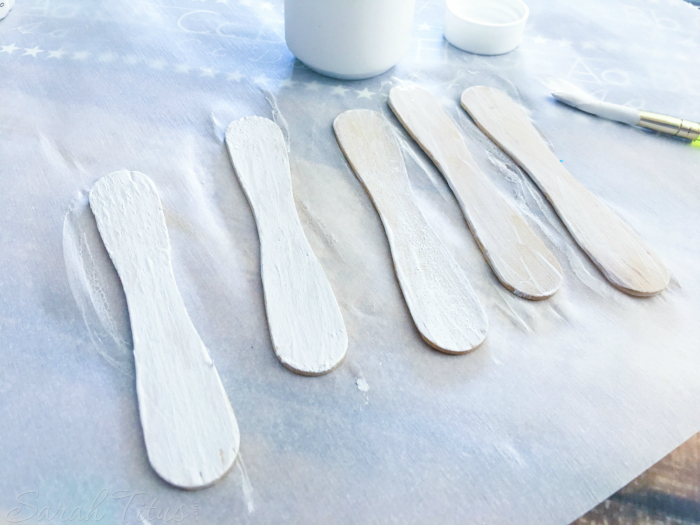 White painted popsicle sticks lying on parchment paper