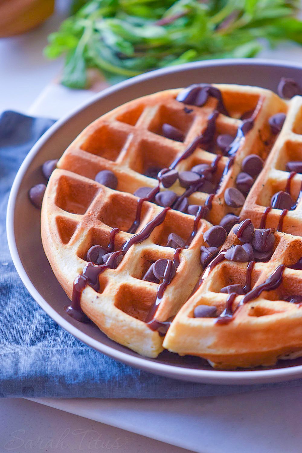 Delicious looking crispy lightly browned waffle covered with drizzled chocolate and chocolate chips