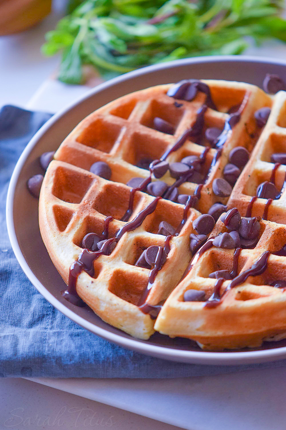 Delicious looking crispy lightly browned waffle covered with drizzled chocolate and chocolate chips