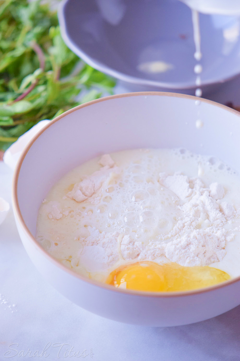 Pouring milk over egg and flour in bowl in preparation for making pizza waffles