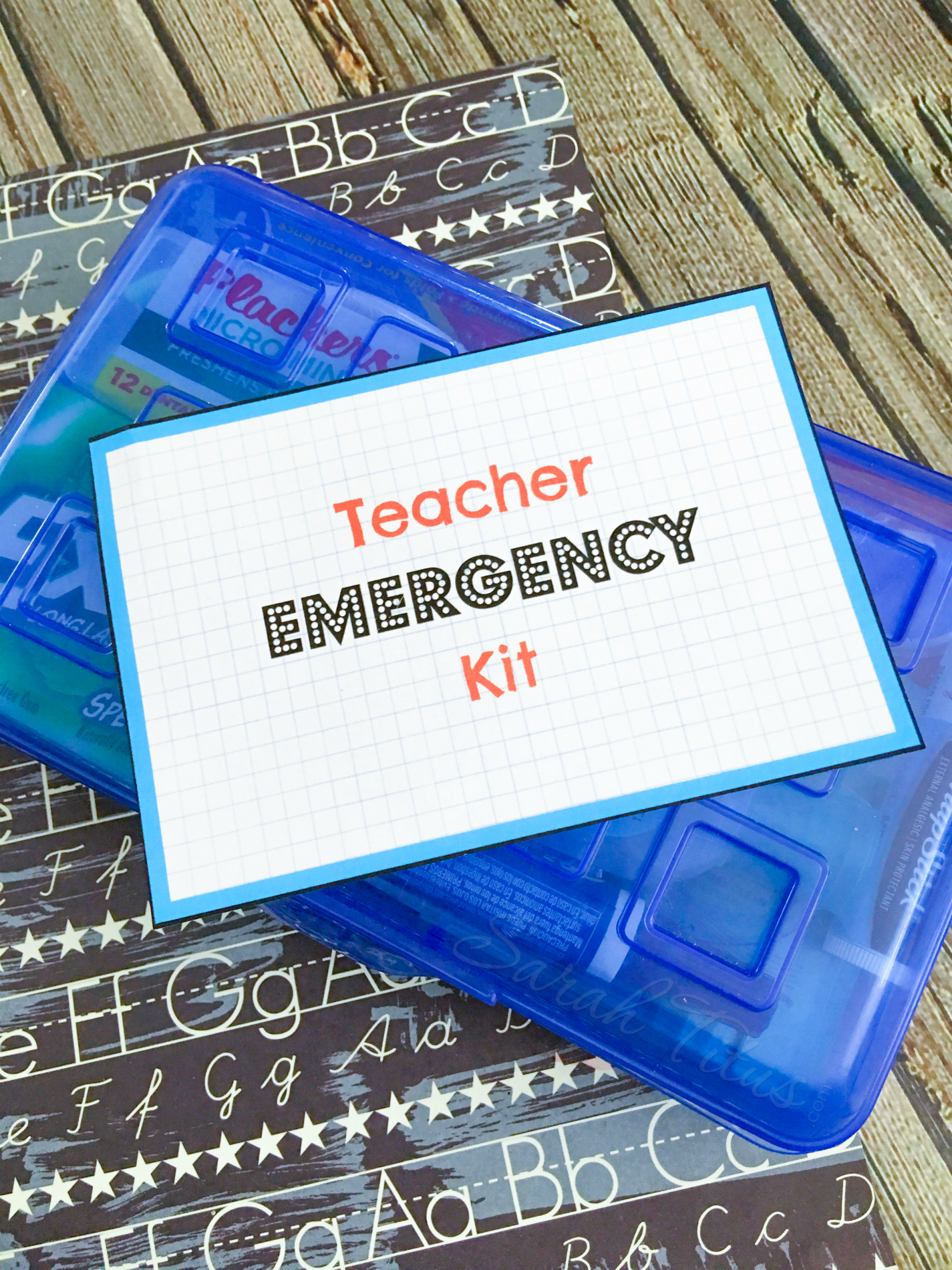 Teacher Emergency Kit Printable on top of blue pencil case, alphabet lettered paper on wooden table