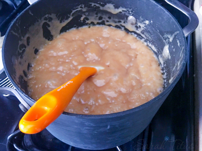 Stirring together gourmet caramel apples ingredients on the stove in a large pot