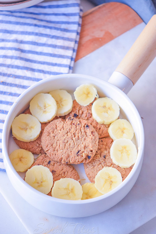 Lining the bottom of a bowl with chocolate chip cookies and sliced bananas