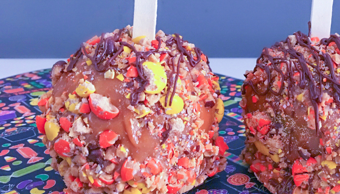 Colorful caramel apples with orange and yellow candy coating, caramel and drizzled chocolate