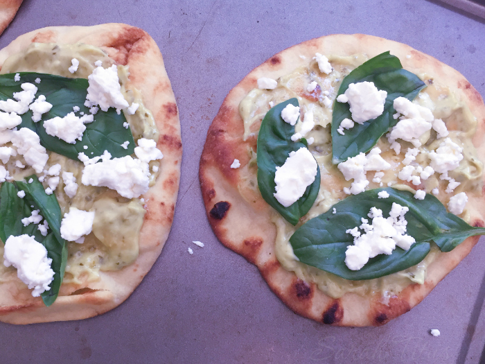 Sprinkling the Feta cheese on top of the basil leaves, pesto and Naan bread