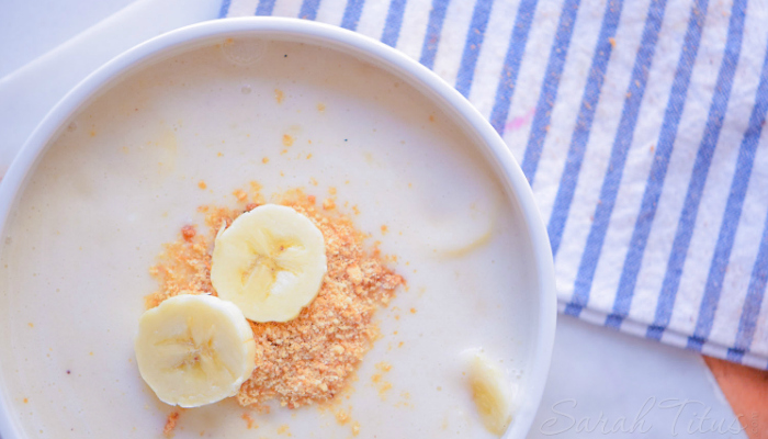 White bowl of banana pudding with fresh sliced bananas and crushed chocolate chip cookies