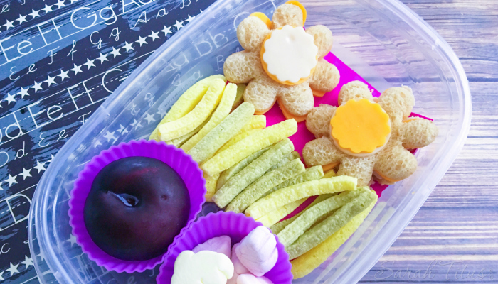 Flower Bento Box with a fresh plum, marshmallows, veggie straws and flower shaped turkey and cheese sandwiches