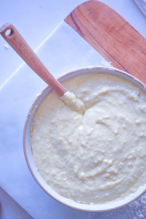 Nutella Swirl Muffins batter being stirred with a wooden spoon sitting on a wooden cutting board