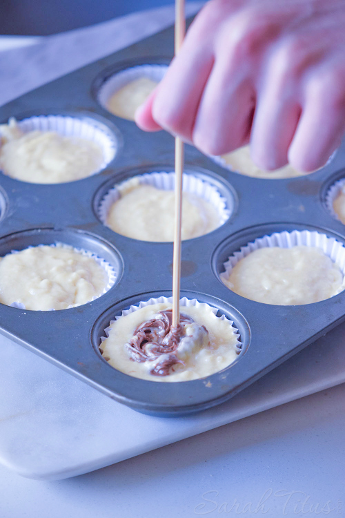 Stirring Nutella into muffin batter in a metal muffin pan