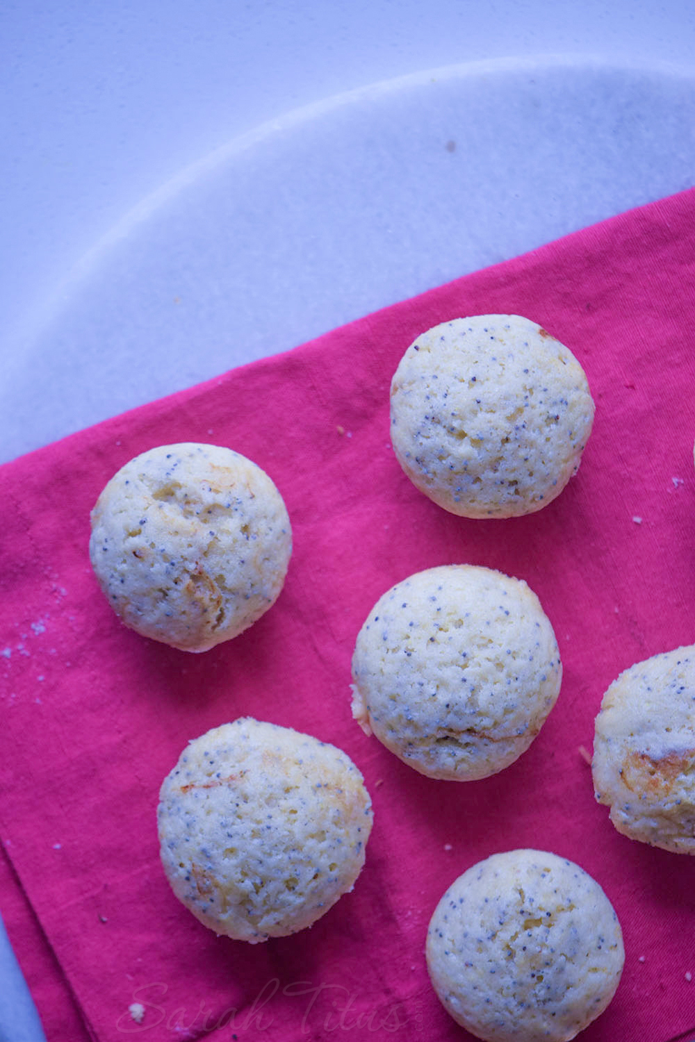 Freshly baked lemon poppy muffins on a pink cloth napkin