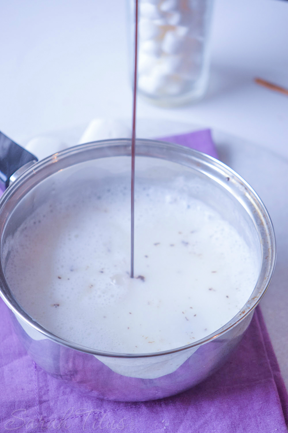 Adding a drizzle of chocolate syrup to the pan of S'mores Hot Cocoa