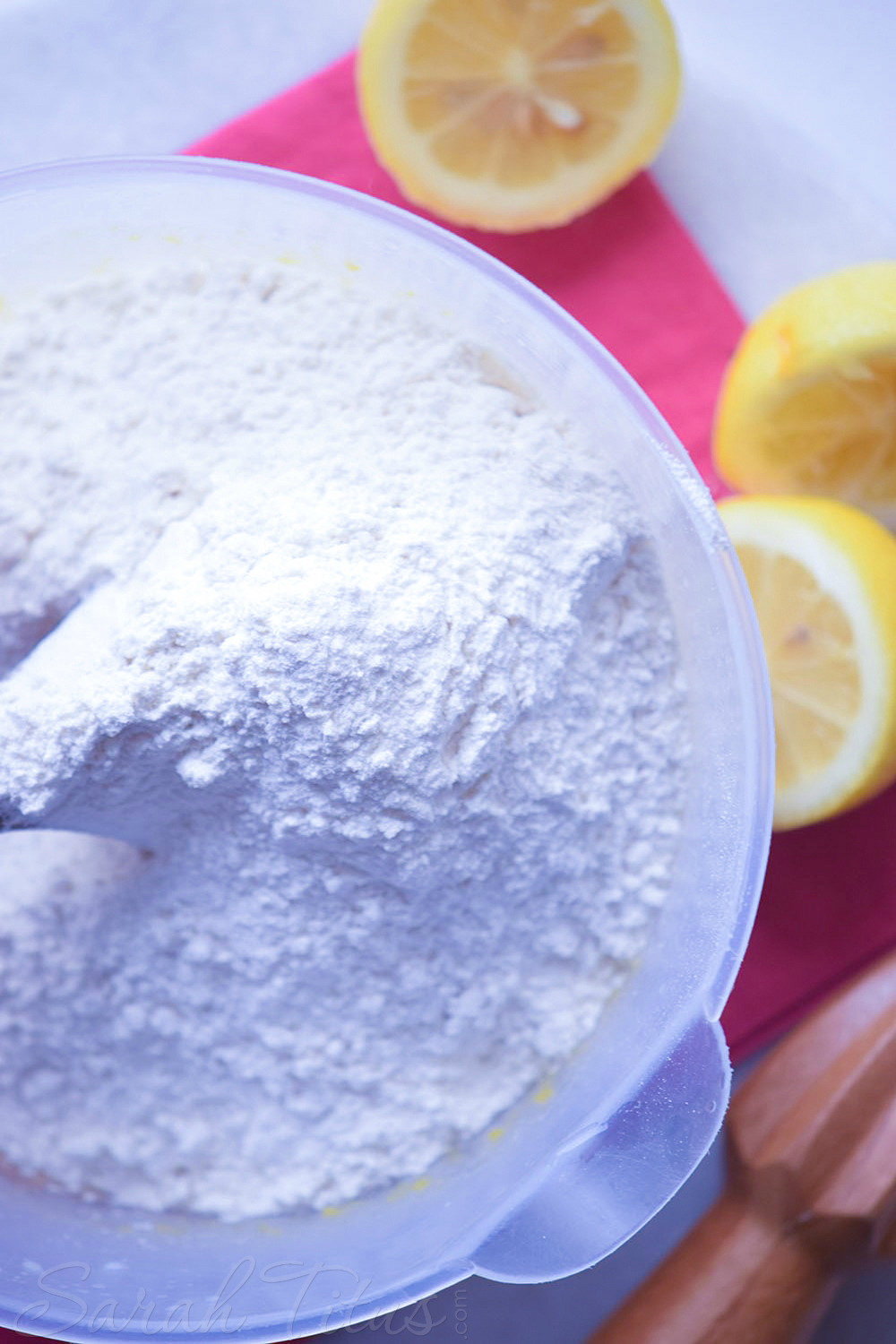 Adding flour to a bowl with lemon poppy muffins liquid ingredients