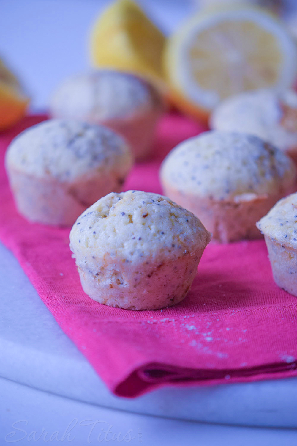 Freshly baked lemon poppy muffins on a pink cloth napkin