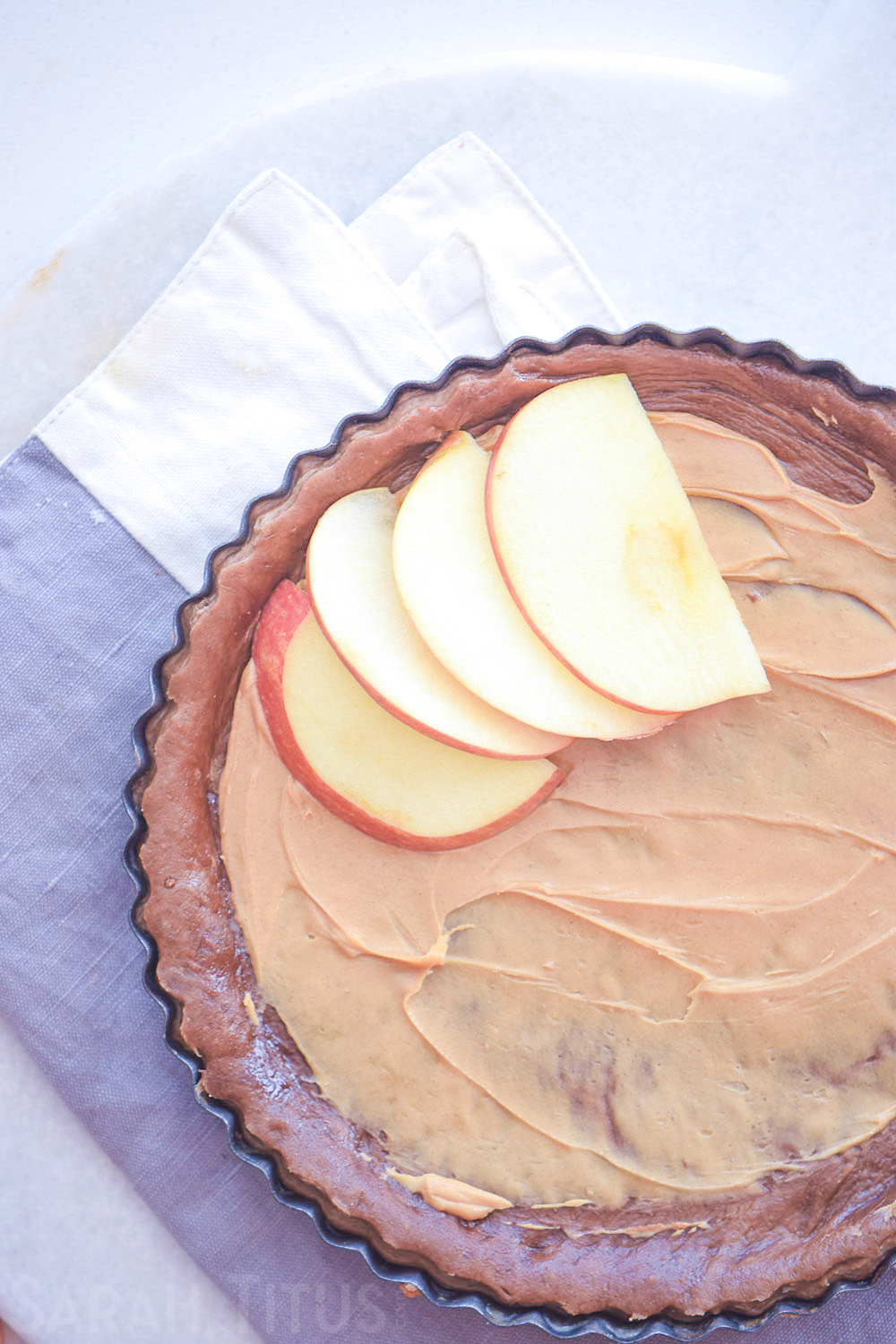 Laying thinly sliced apples on top of the peanut butter layer on the chocolate pie crust