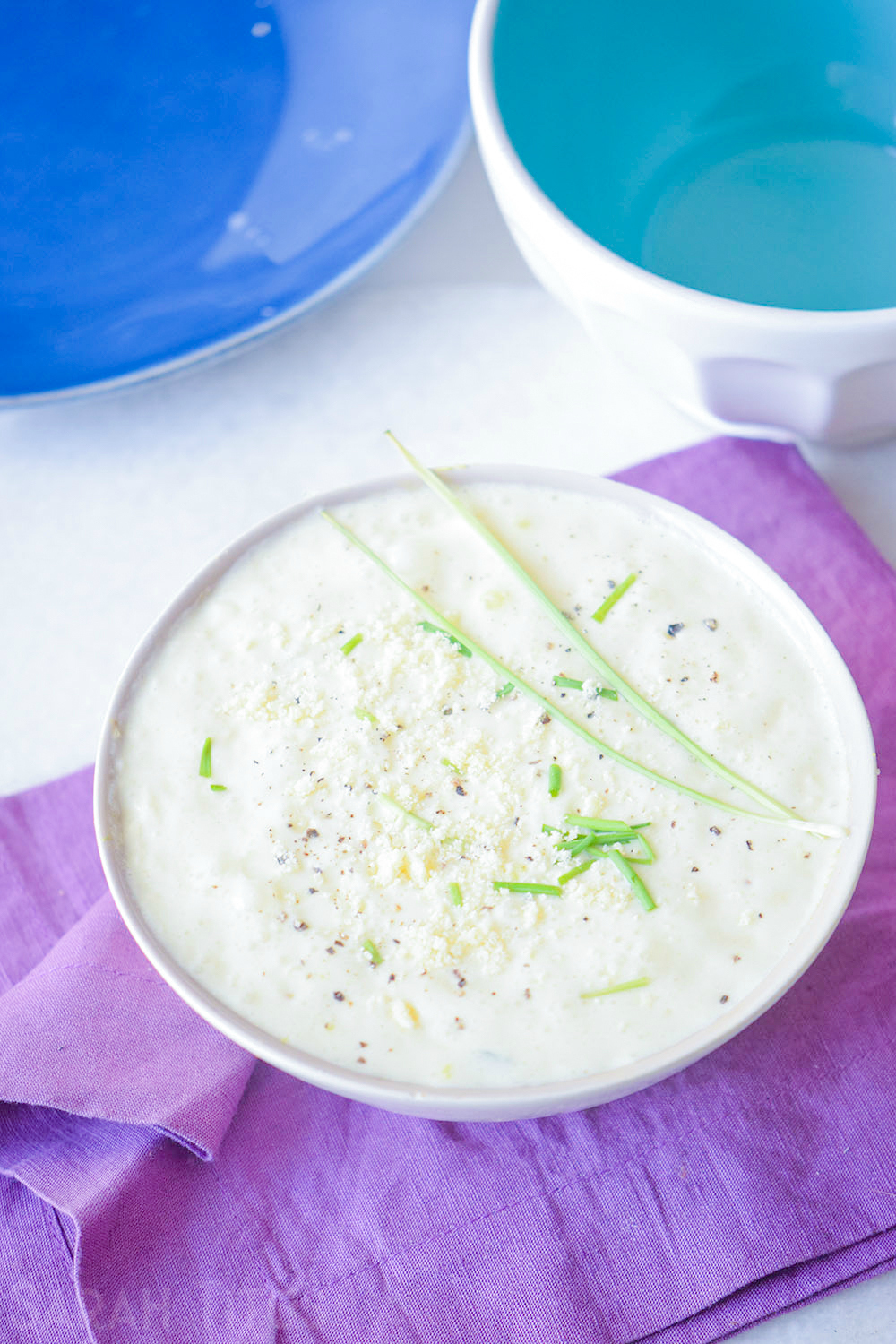 Serving potato soup with Parmesan cheese, chives and pepper