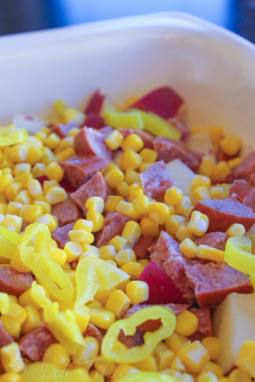 Adding corn and pepperchini's to the Potato and Polish Sausage Bake.