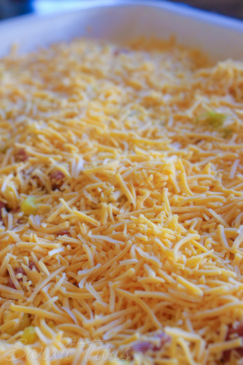 Adding milk and cheese to the top of the Potato and Polish Sausage Bake.