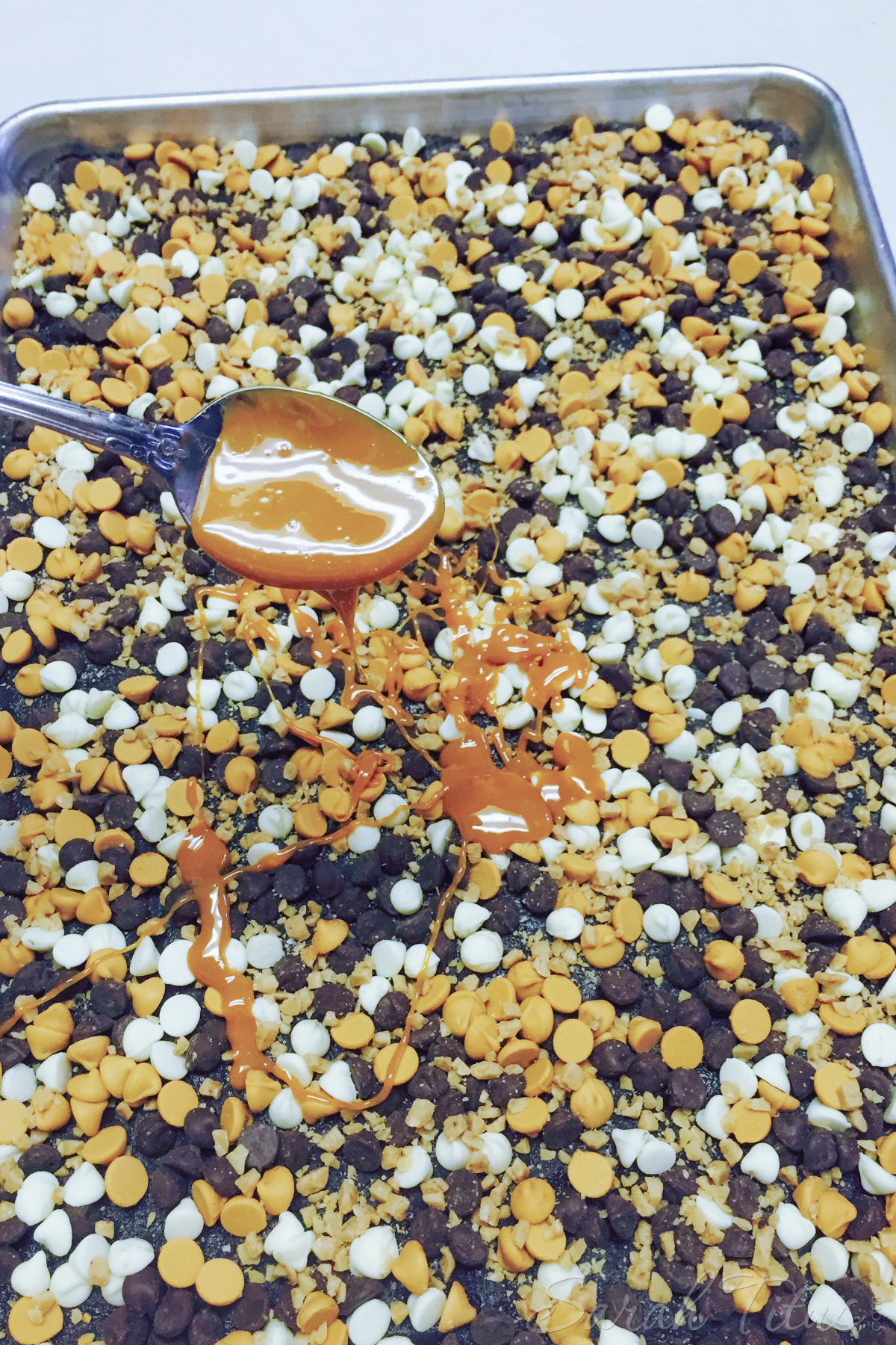 Drizzling melted caramel over the Salted Caramel Magic Bars in a silver baking dish