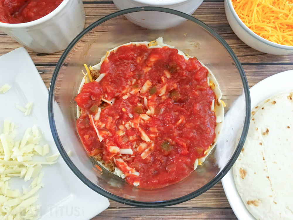 Adding a layer of salsa to the glass bowl for the taco bake