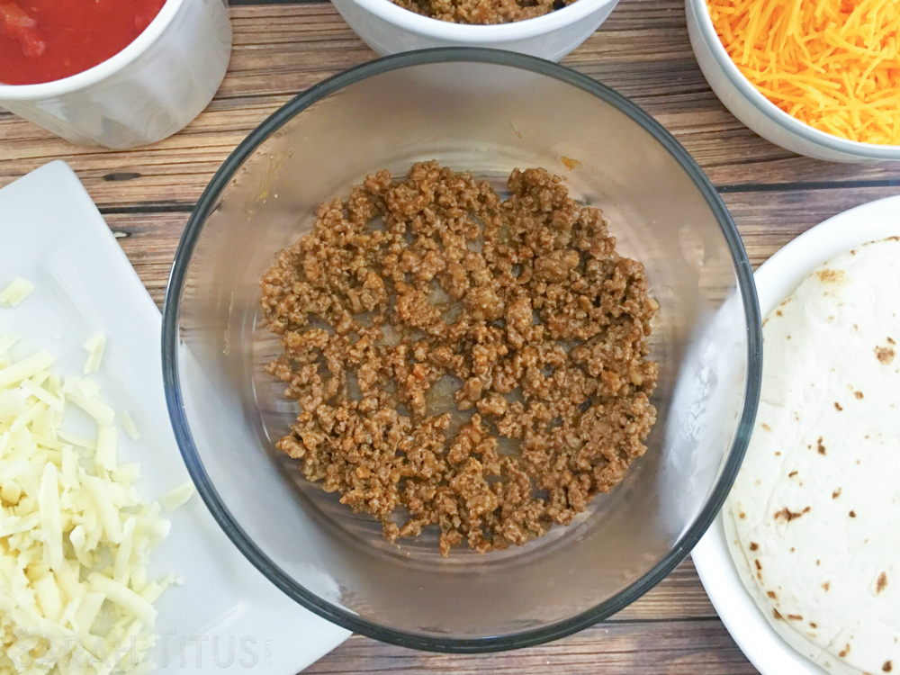 Ingredients for the taco bake: salsa, cheeses and tortillas with the beef layered on the bottom of a glass bowl