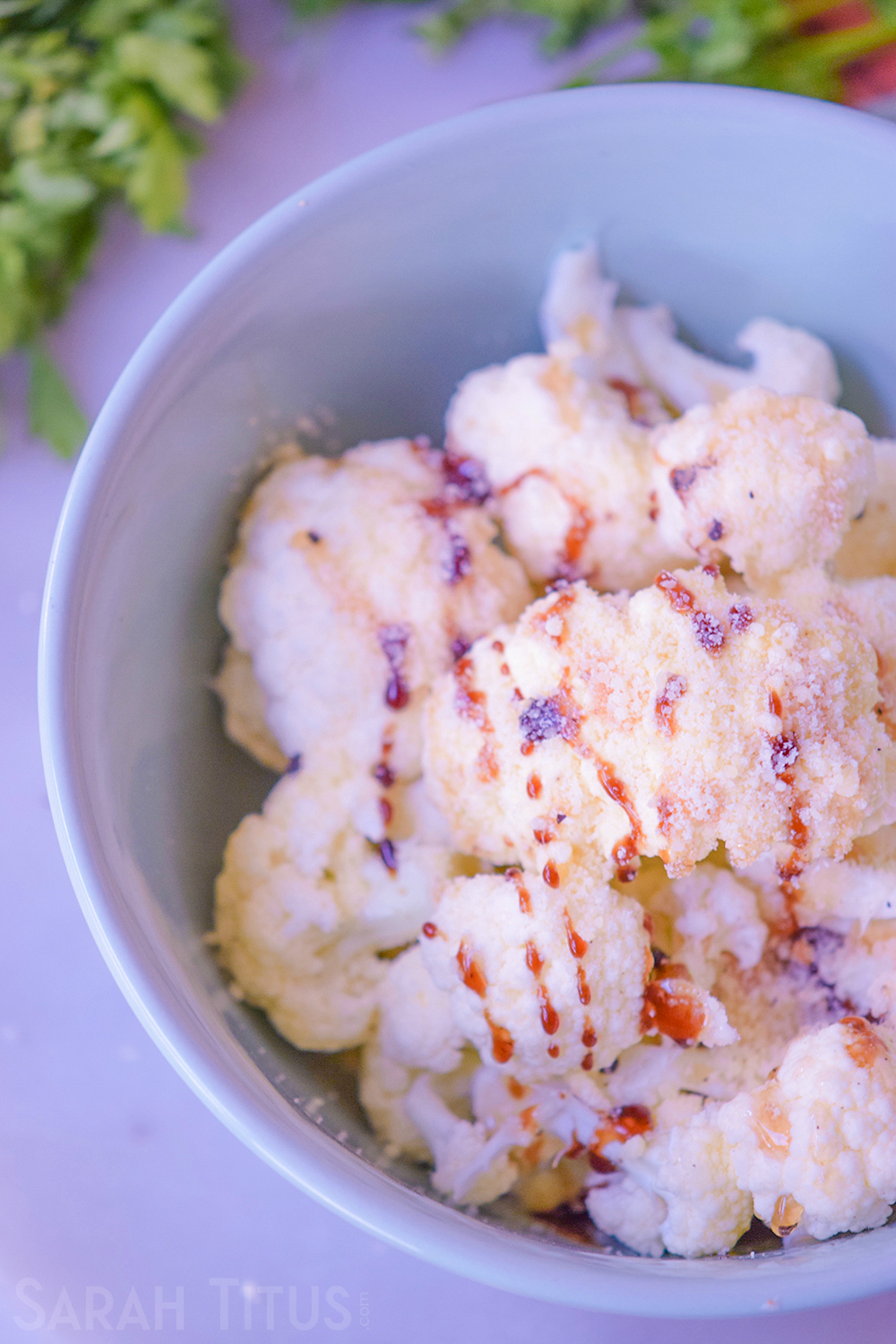 Topping the chopped cauliflower pieces with balsamic vinegar in a bowl