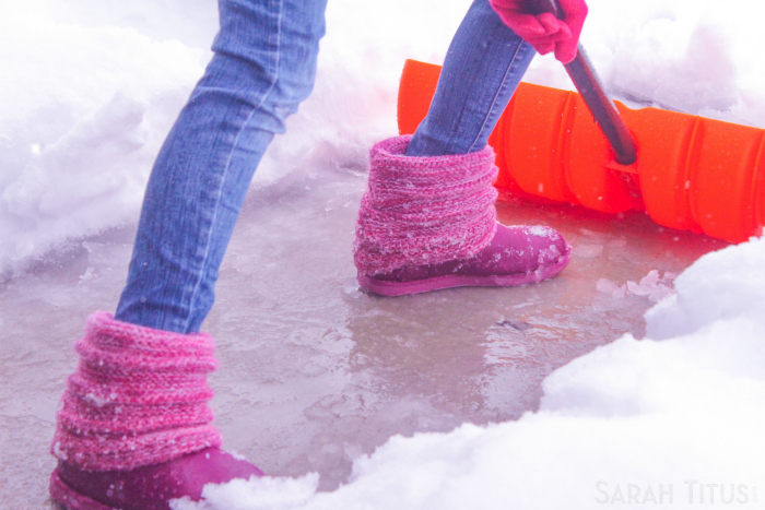 Woman shoveling snow because she has to go to the grocery store.