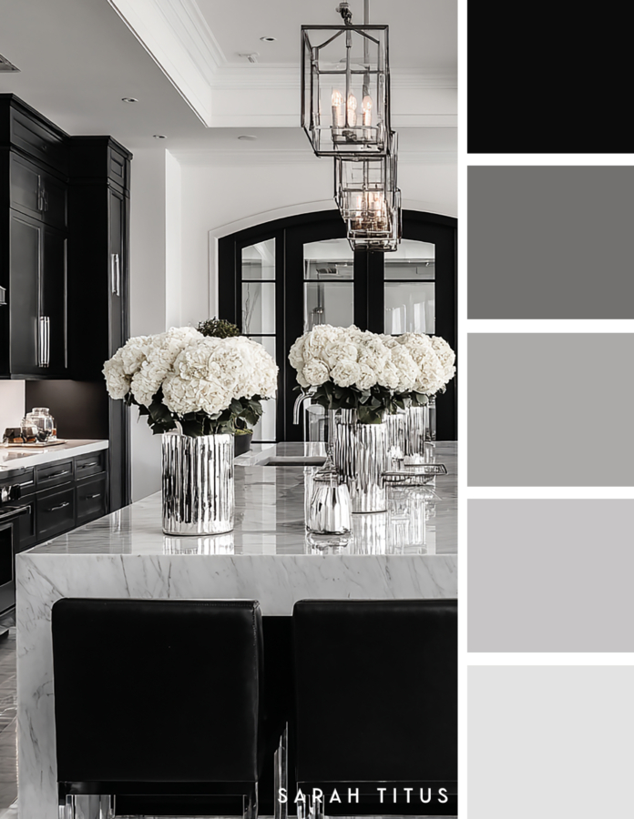 Black and white luxury kitchen with a marble island, black cabinet stools, silver lantern pendant lights, and white hydrangeas with a black, gray, and silver color palette.