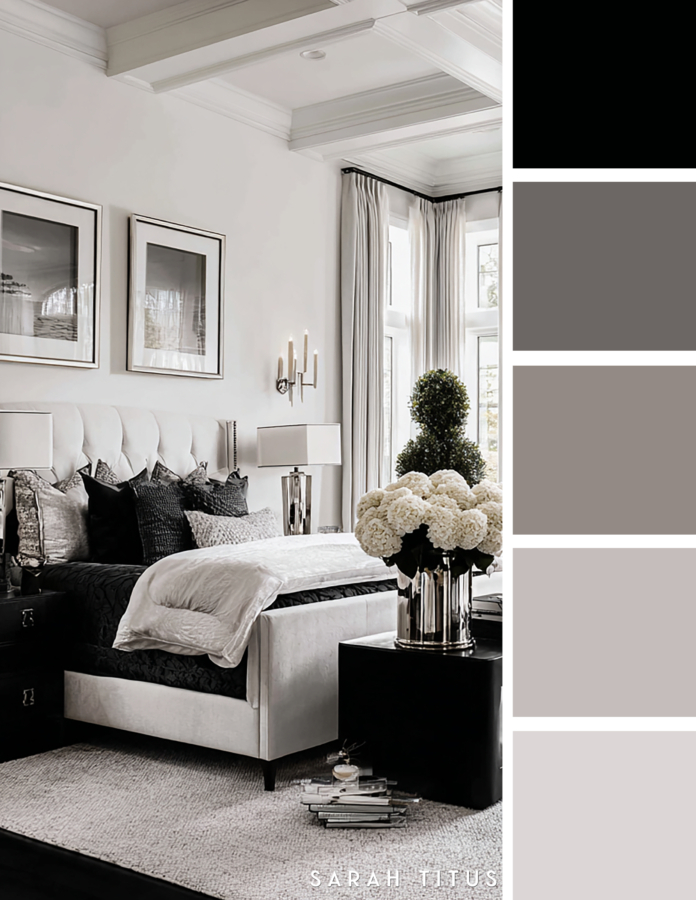 Sophisticated black and white bedroom with layered bedding, silver lamps, white flowers, dark nightstands, and soft gray accents in a luxe neutral palette.