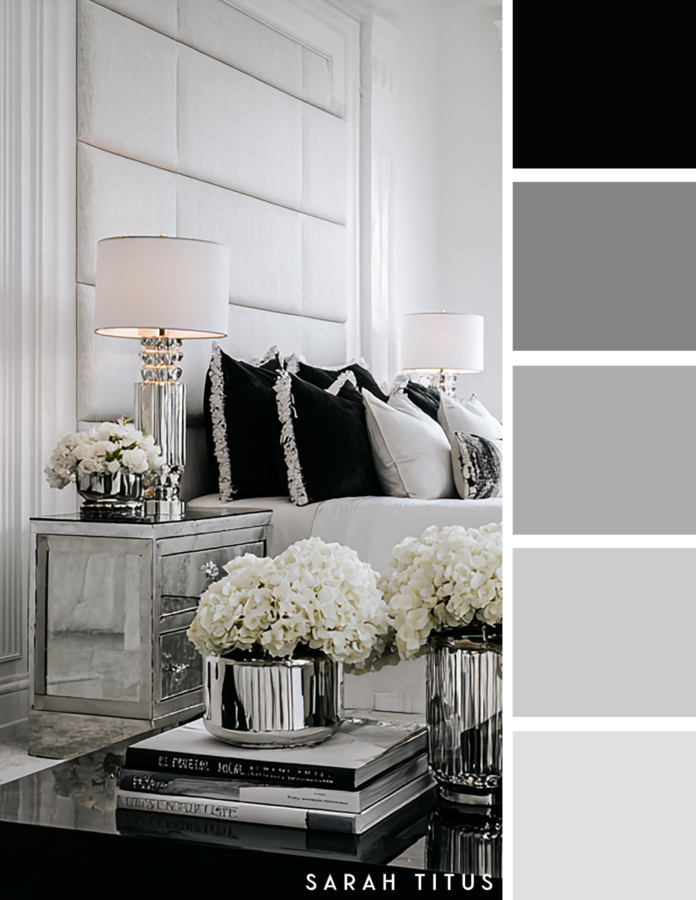 Elegant black and white bedroom with a tall upholstered headboard, mirrored nightstand, silver lamps, black accent pillows, and white hydrangeas in a soft gray and silver palette.
