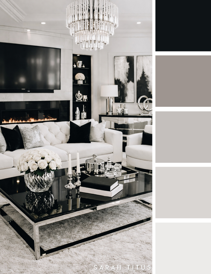 Chic black and white living room with a crystal chandelier, white tufted sofa, glossy black coffee table, fireplace, and silver decor in a luxe gray and silver palette.