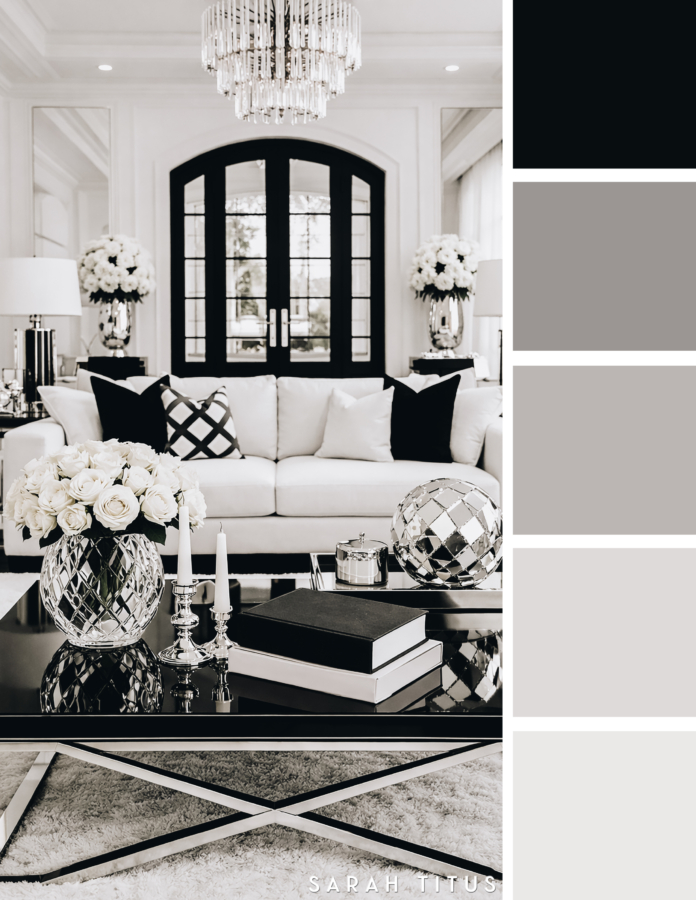 Sophisticated black and white living room with white sofa, black coffee table, crystal chandelier, silver accents, and black framed French doors in a modern neutral palette.